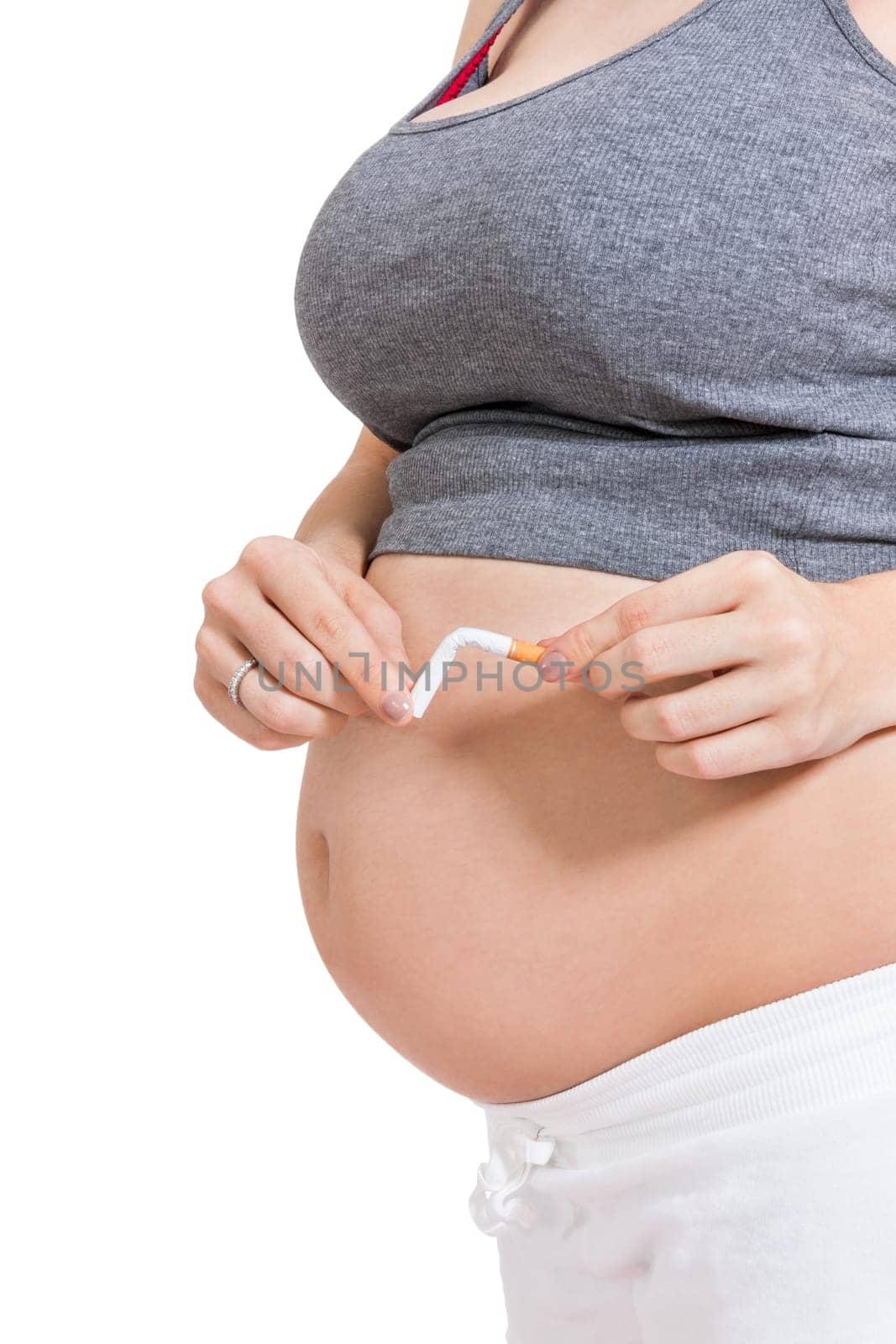 Pregnant woman breaks a cigarette in front of her baby belly isolated against white background