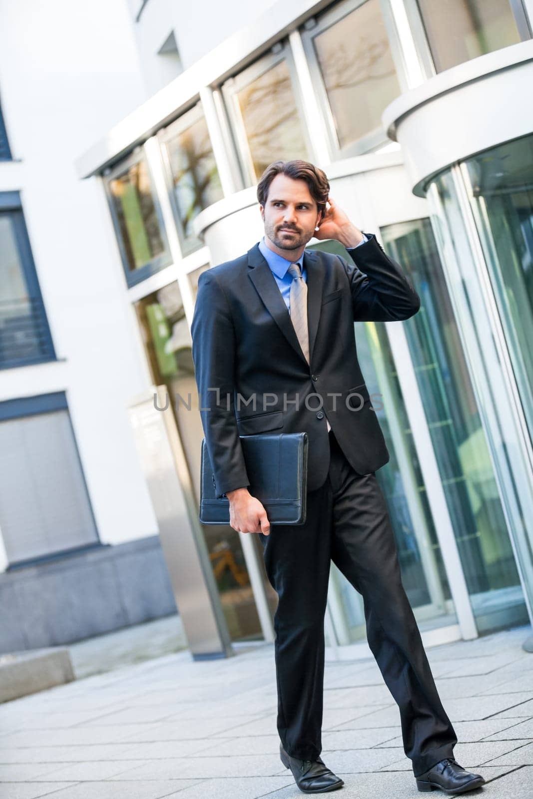 Young trendy businessman in front of a business building successfully with beard and dark hair