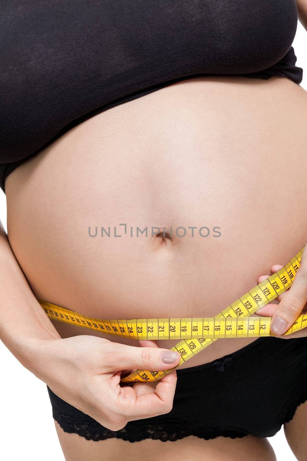 Pregnant woman with a measuring tape measures her girth on her abdomen isolated against a white background