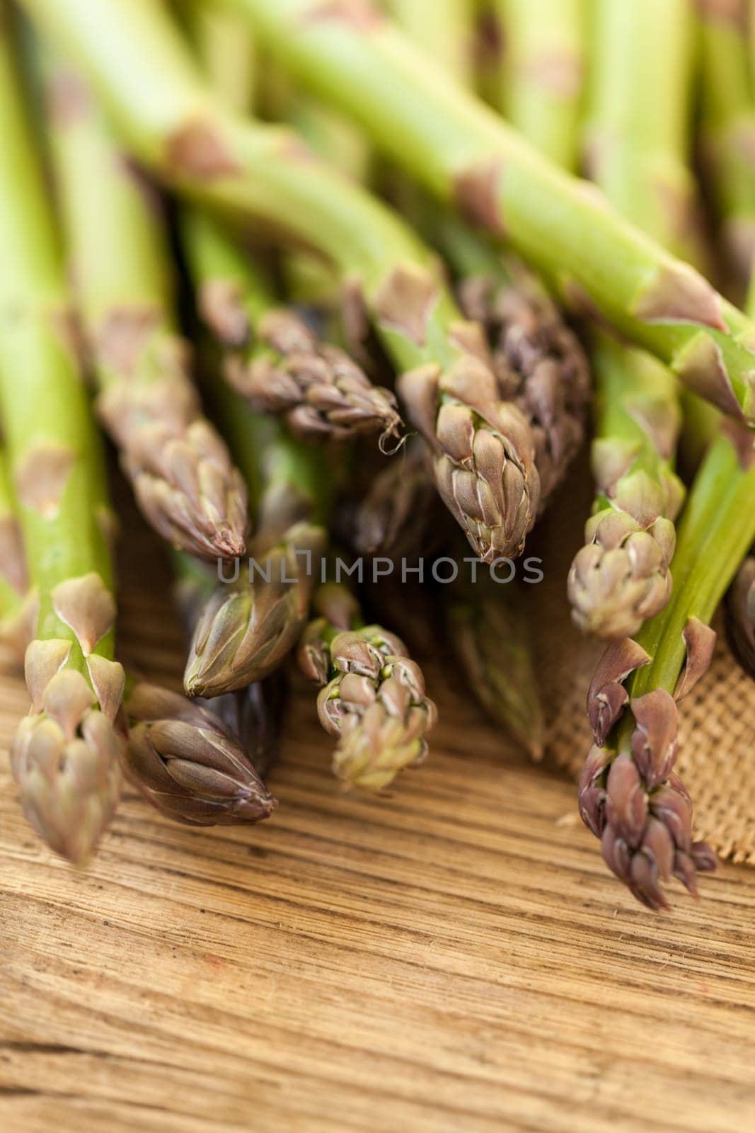 Fresh healthy green asparagus as a close-up on a wooden table in sunlight