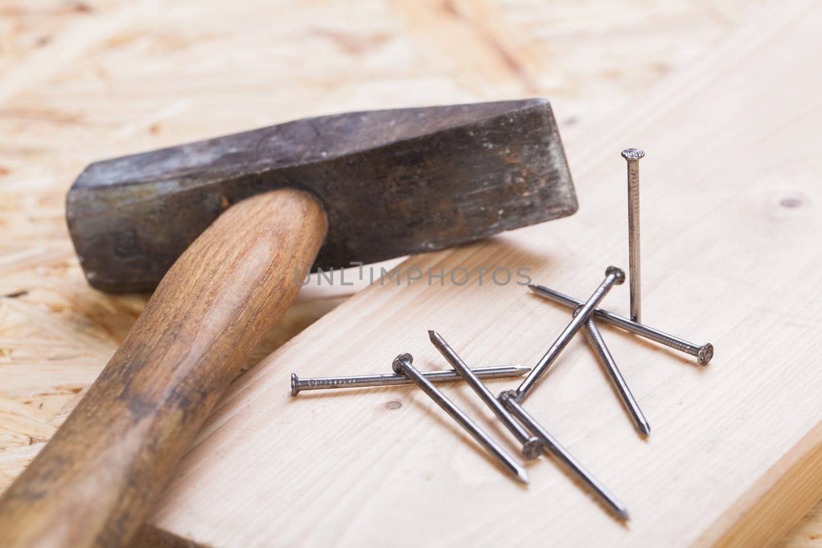 Hammer with nails on a wooden board in a workshop of a do-it-yourselfer