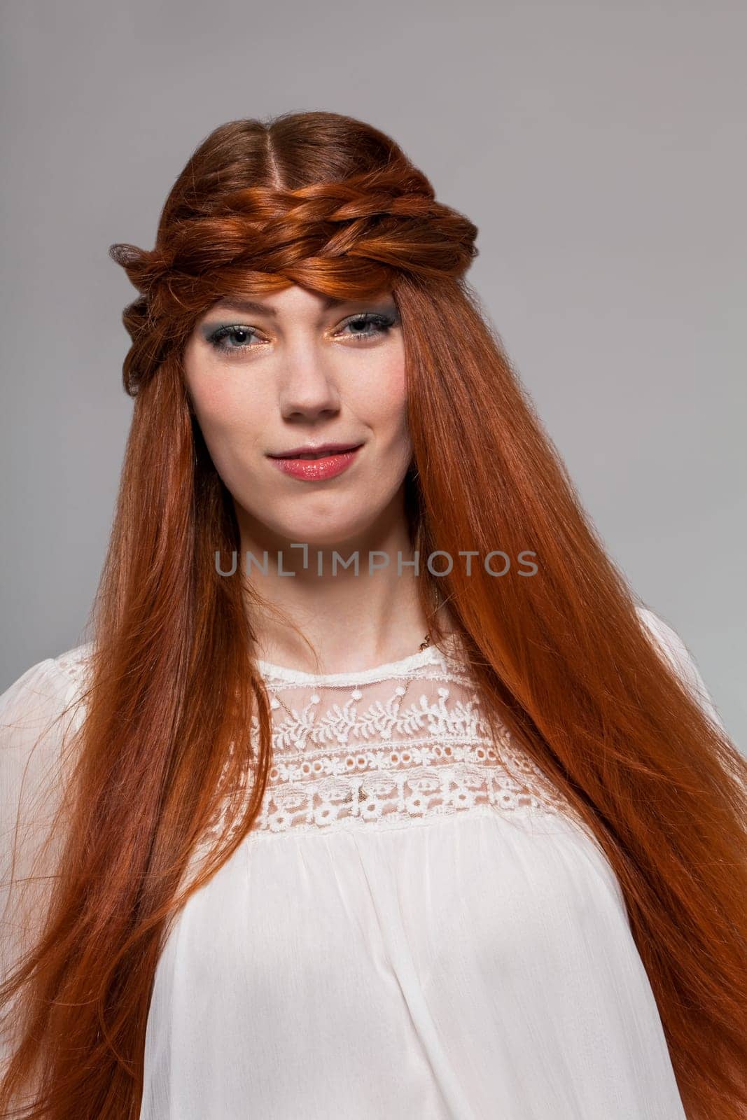 Young attractive female girl with long red hair in portrait against grey background
