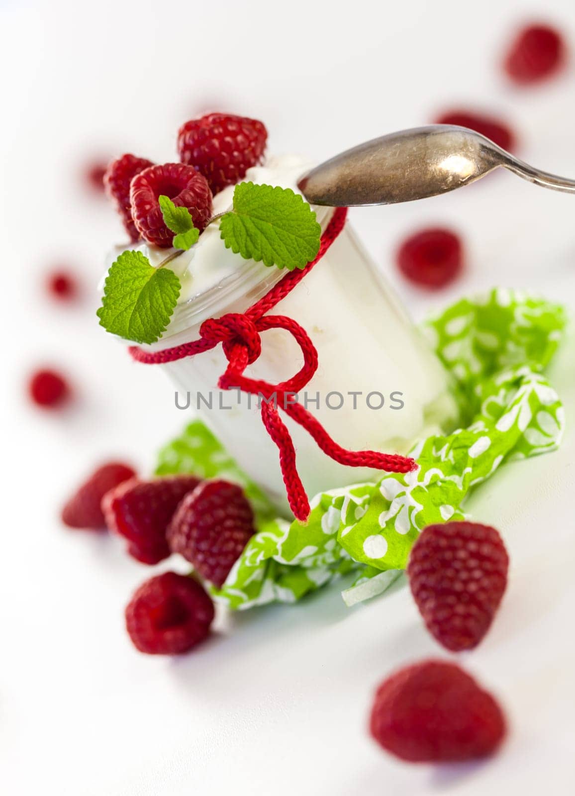 Fresh yoghurt with raspberries in a glass insulated on a white background