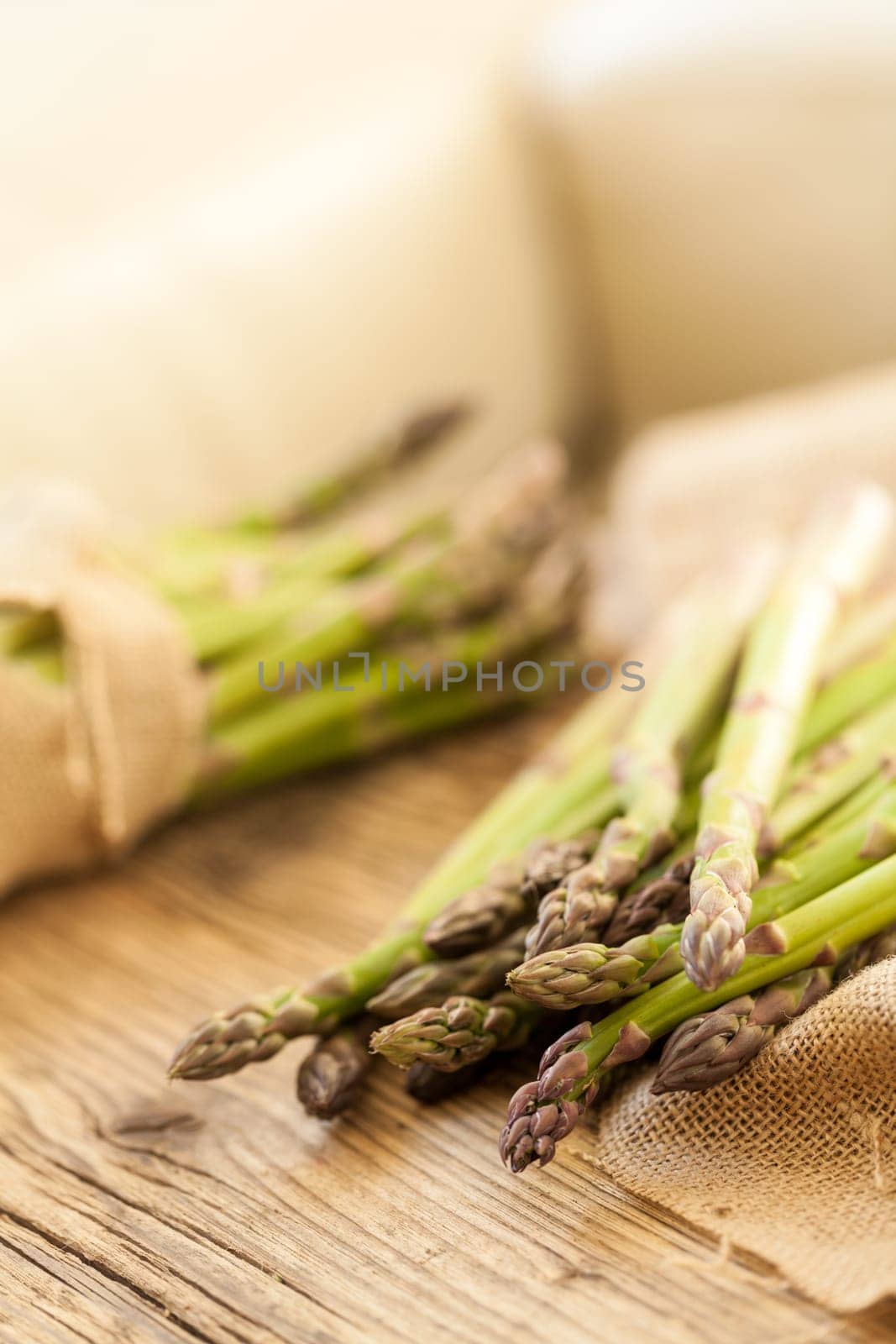 Fresh healthy green asparagus as a close-up on a wooden table in sunlight