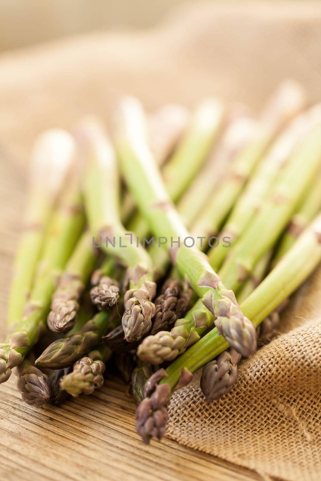 Fresh healthy green asparagus as a close-up on a wooden table in sunlight