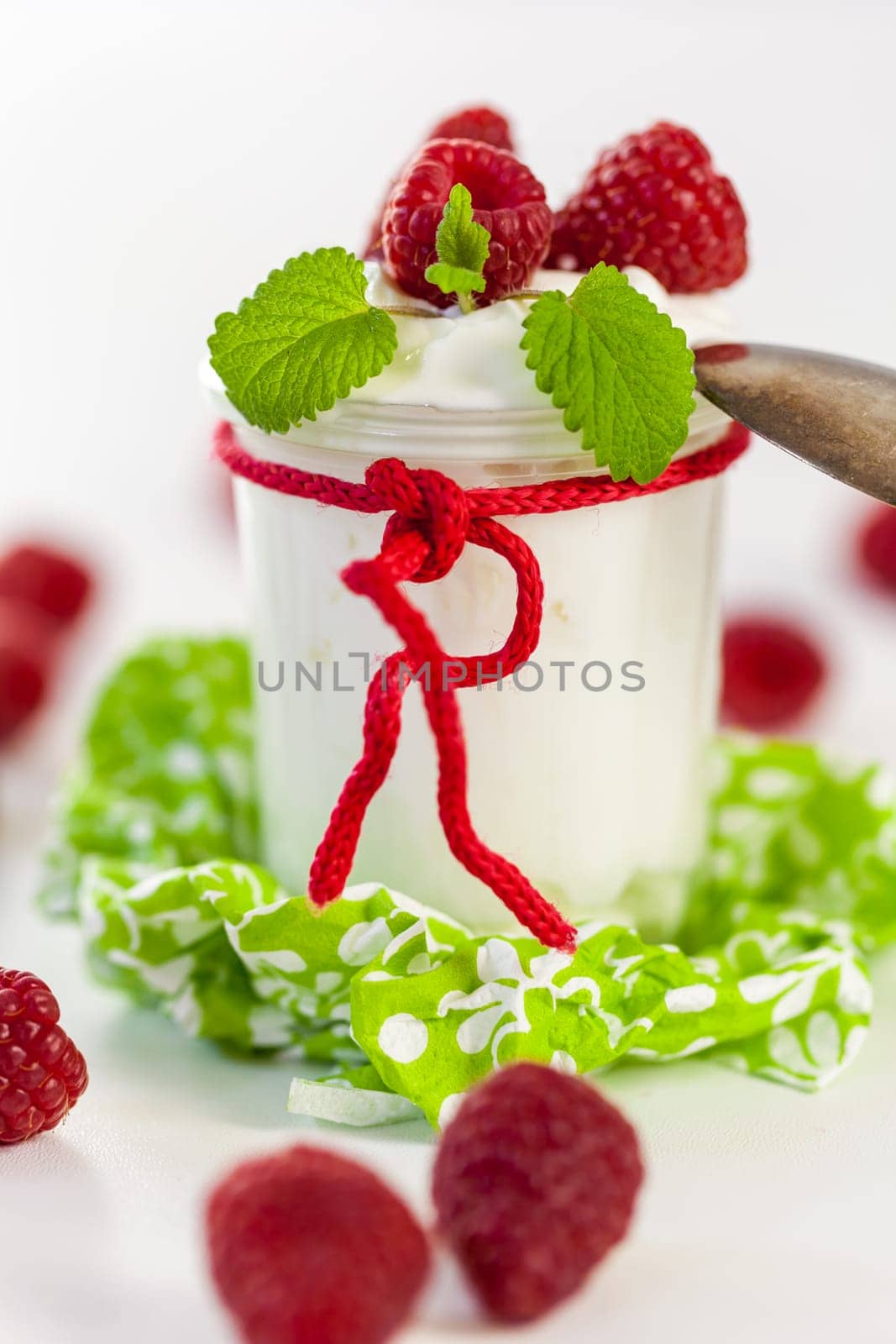Fresh yoghurt with raspberries in a glass insulated on a white background