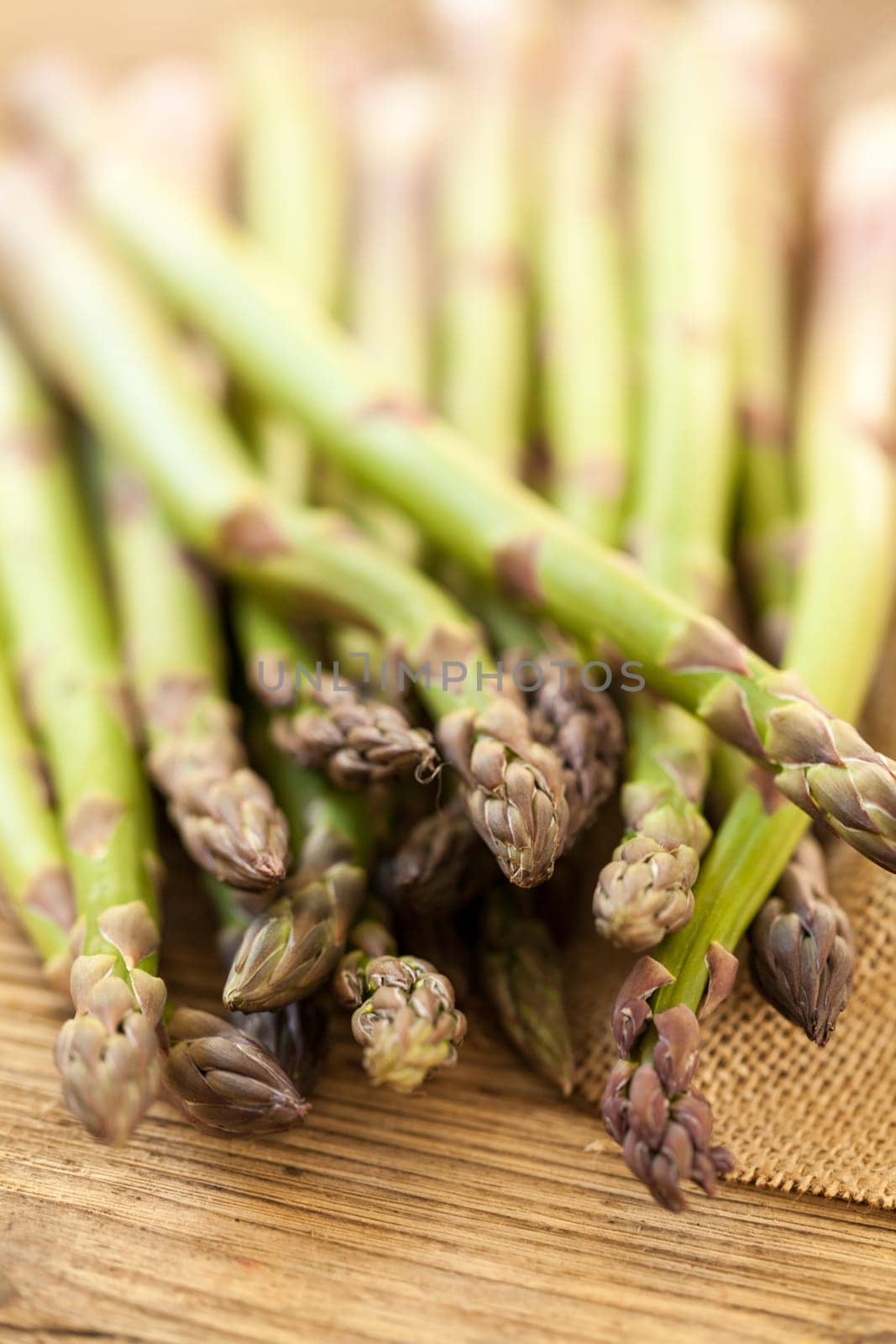 Fresh healthy green asparagus as a close-up on a wooden table in sunlight