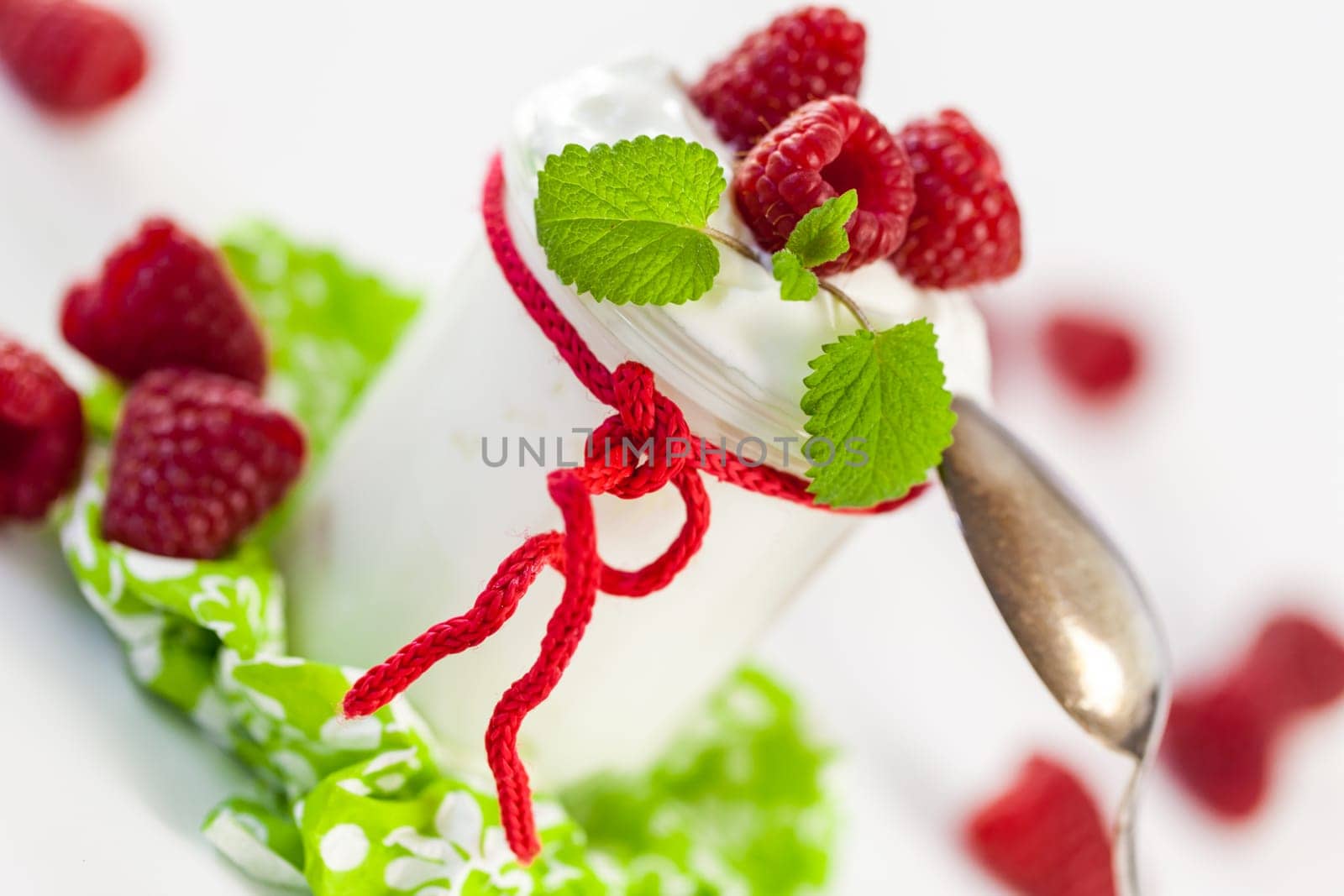 Fresh yoghurt with raspberries in a glass insulated on a white background