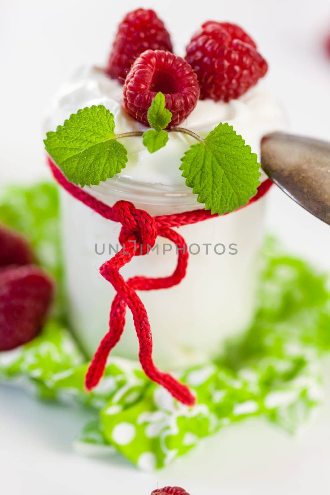 Fresh yoghurt with raspberries in a glass insulated on a white background