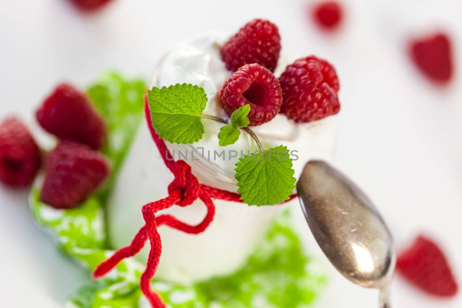 Fresh yoghurt with raspberries in a glass insulated on a white background