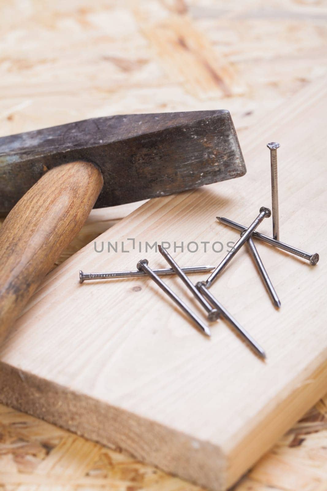 Hammer with nails on a wooden board in a workshop of a do-it-yourselfer