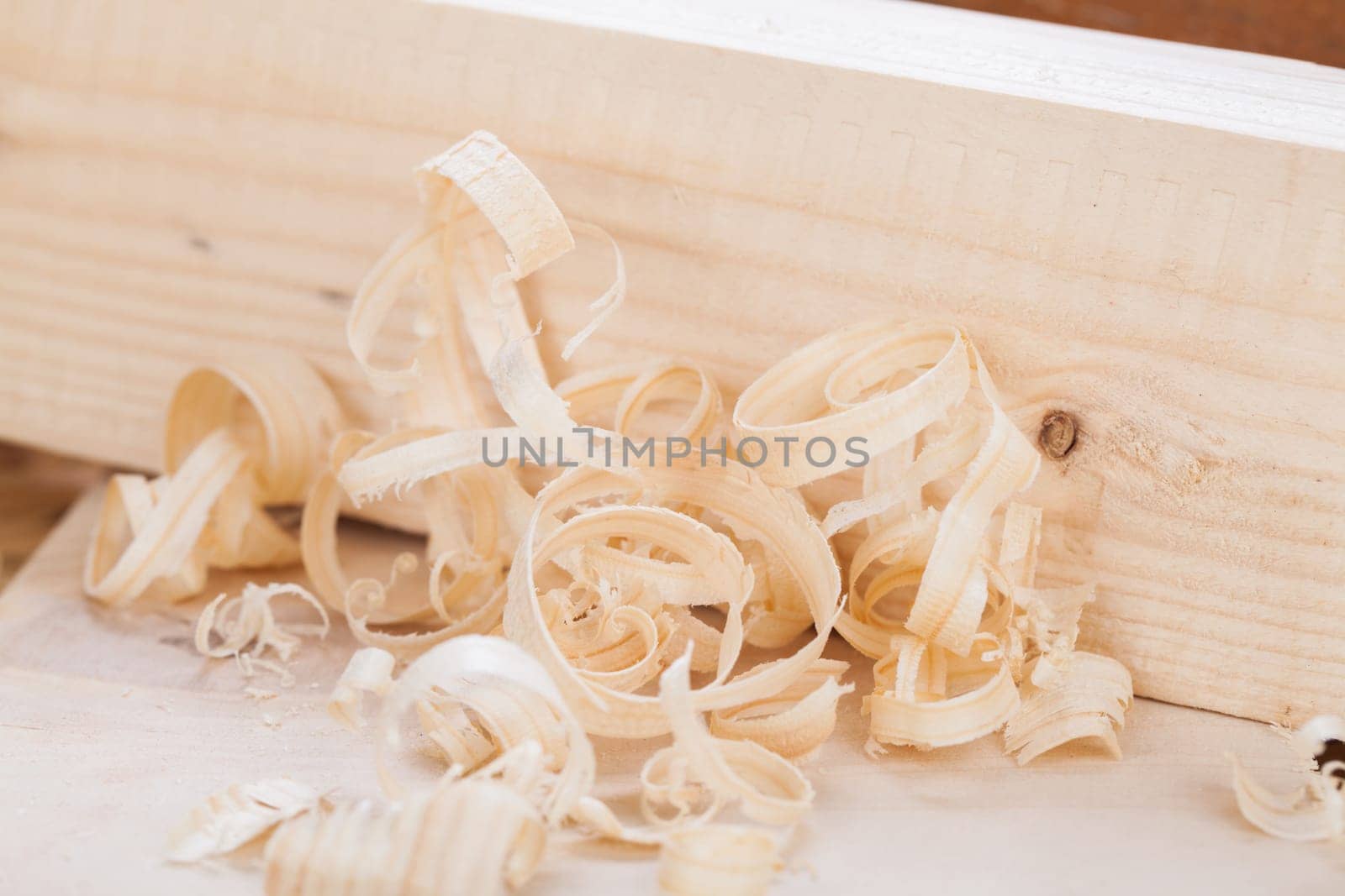 Planing with wood chips in a carpentry shop during woodworking in close-up detail