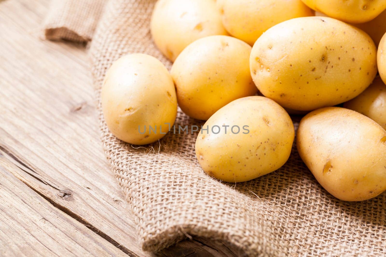 Fresh new potatoes on a jute sack with a green background as a close-up