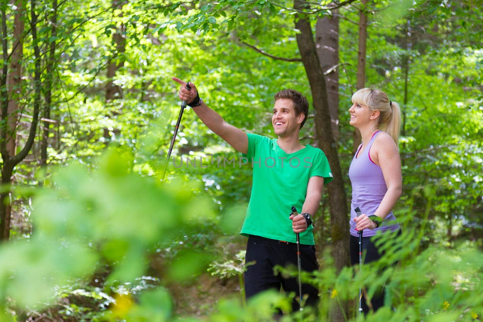 Young spoty active cople with hiking sticks walking in nature. Active lifestyle. Activities and recreation outdoors.