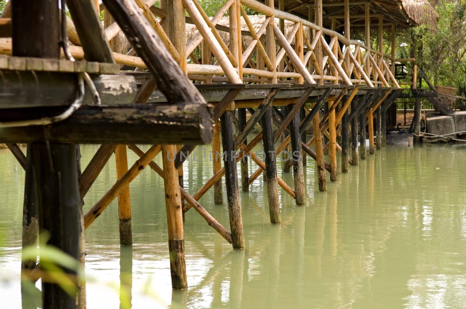 The base of wooden bridge over lake in garden