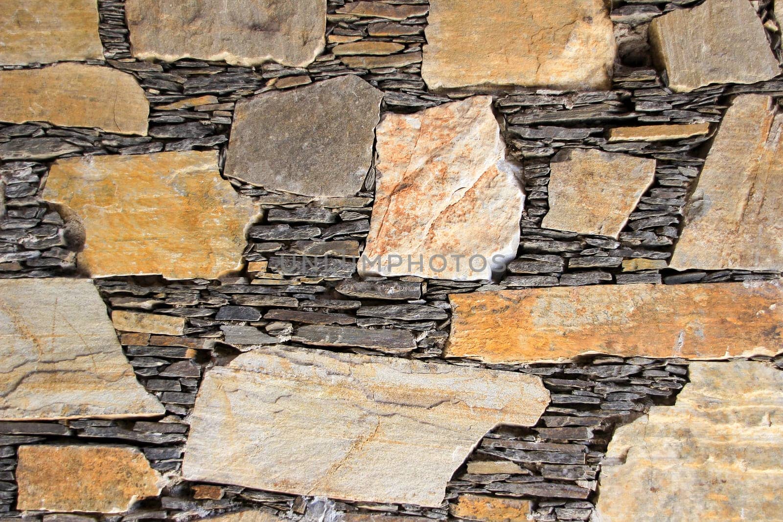 Beautiful mosaic of stones and slabs neatly stacked in wall
