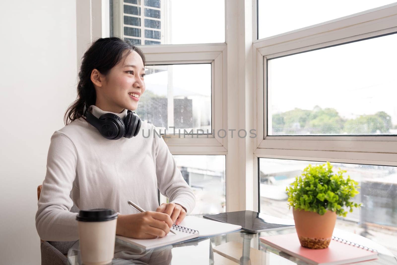 Beautiful young asian woman sitting and taking note on the desk at house. Happy smiling working online, Freelance work at home.