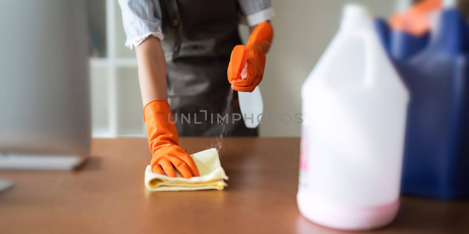 Asian woman cleaning in work room at home. Young woman housekeeper cleaner use a cloth to wipe equipment for working. concept housekeeping housework cleaning by nateemee