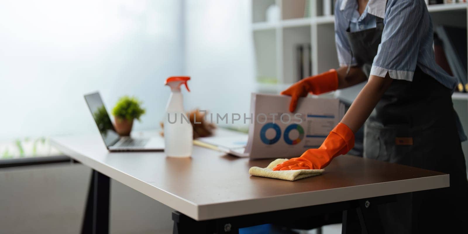 Asian woman cleaning in work room at home. Young woman housekeeper cleaner use a cloth to wipe equipment for working. concept housekeeping housework cleaning by nateemee