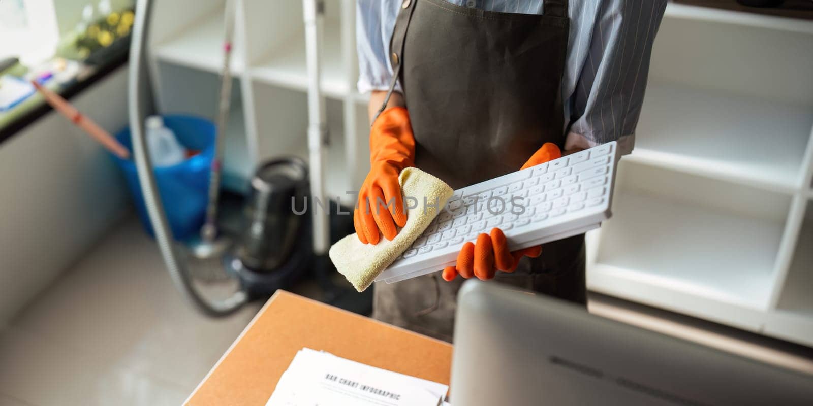 Asian woman cleaning in work room at home. Young woman housekeeper cleaner use a cloth to wipe equipment for working. concept housekeeping housework cleaning by nateemee