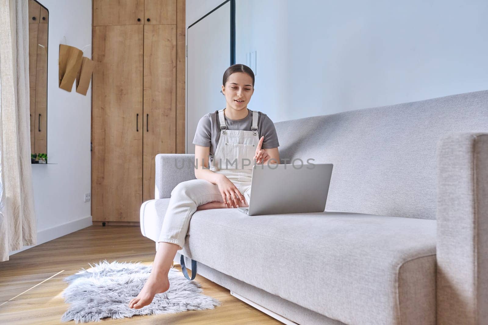 Teen girl at home lying on couch using laptop. Technology for learning leisure communication, modern lifestyle, adolescence concept