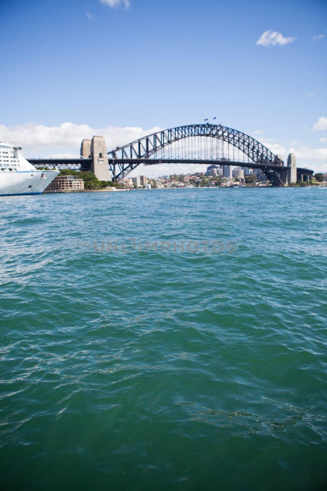 View of Sydney Harbour Bridge in Australia looking of green colored water with front of cruise ship in corner