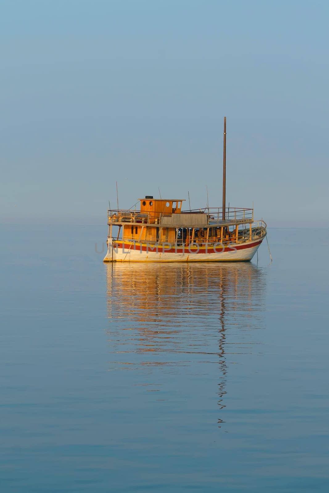 Small traditional Adriatic sailboat  moored in calm sea. Shooted at the "golden hour"""