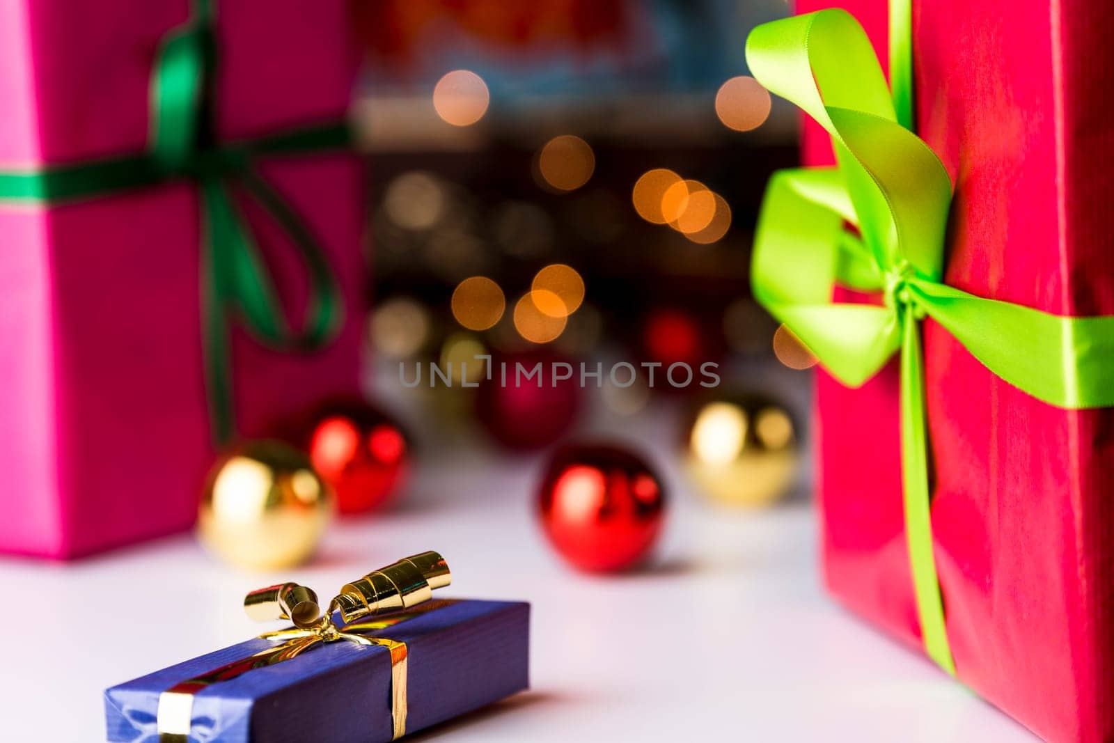 Baubles and glitters in soft focus contrasting with the sharp outlines of the blue wrapped gift in front..