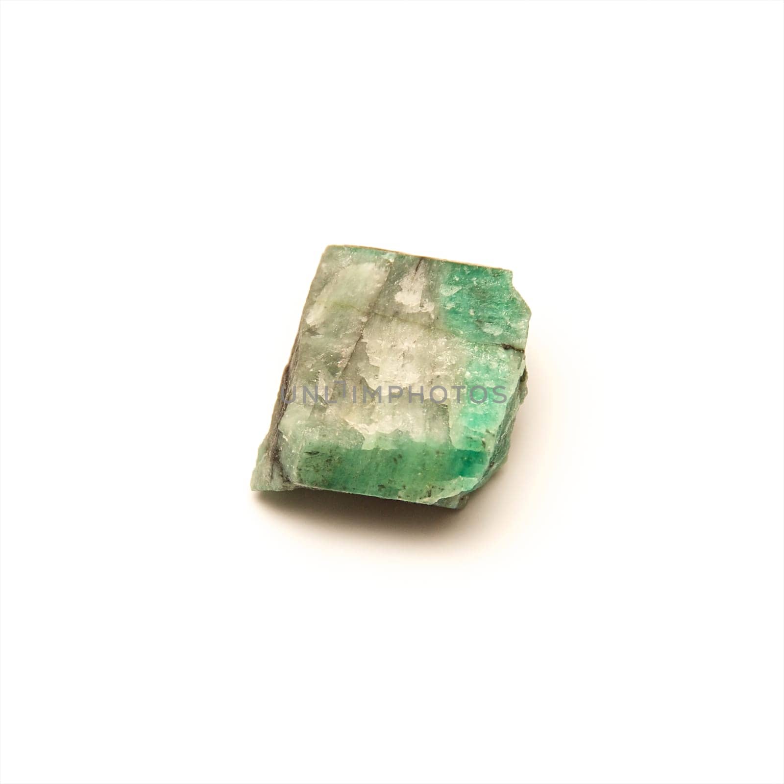 A close up of raw uncut piece of emerald shot over white.