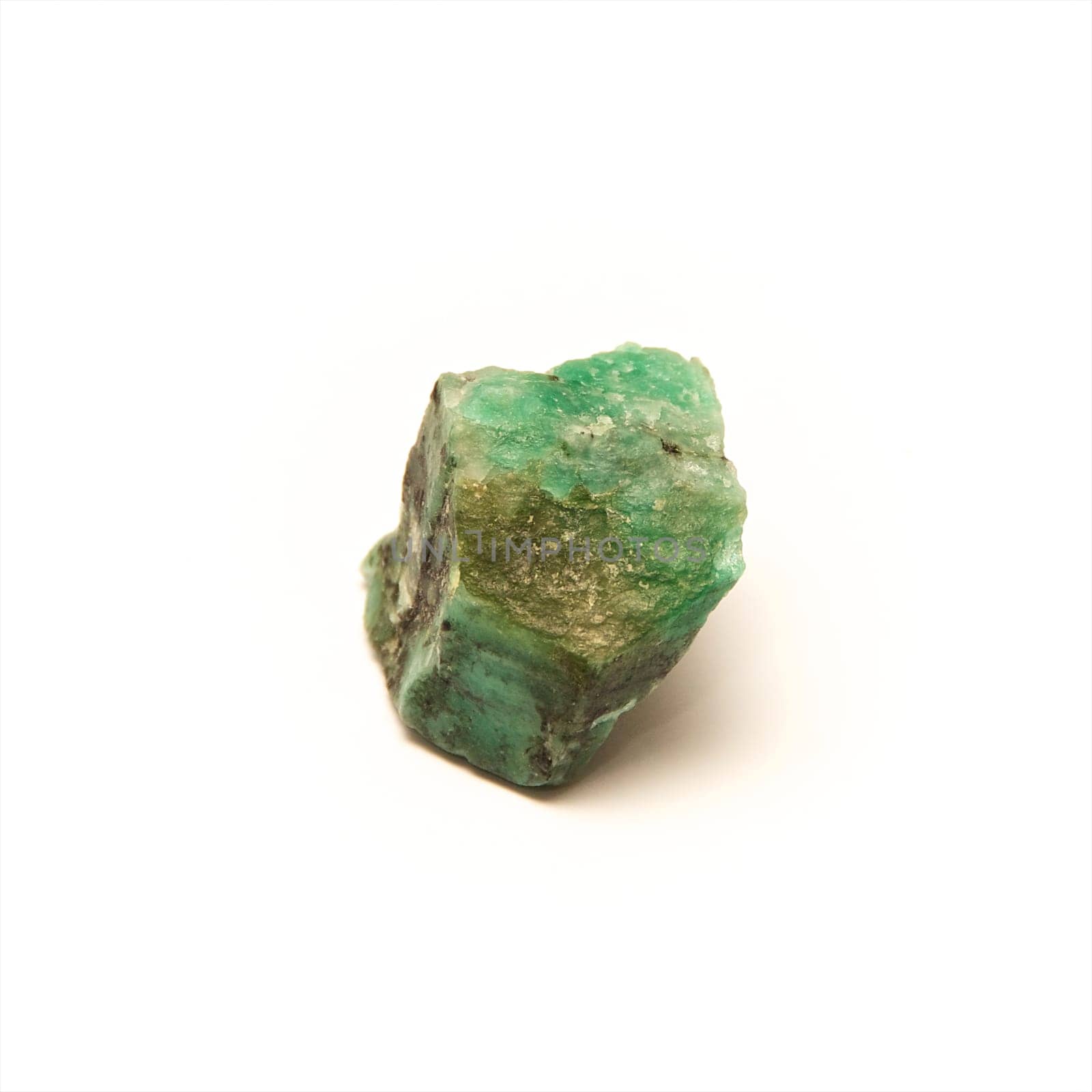 A raw uncut piece of emerald shot over white.