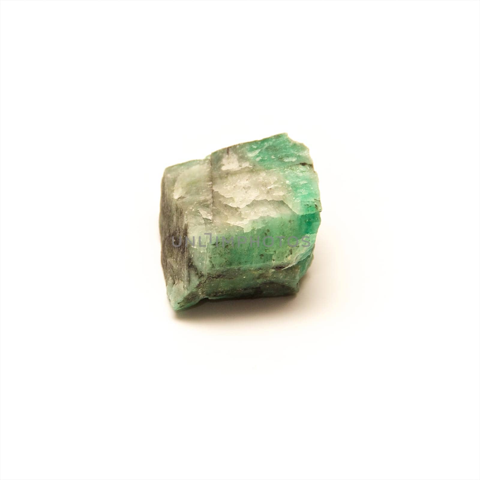 A raw uncut piece of emerald shot over white.