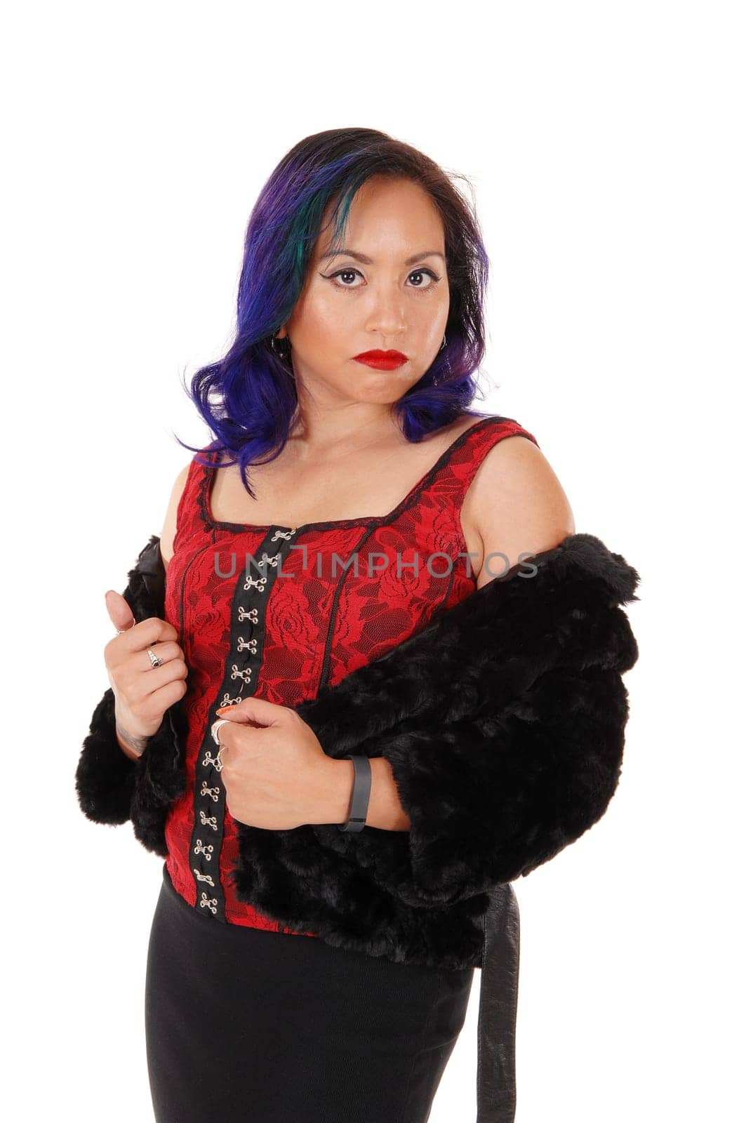 A pretty Asian woman in a red corset and black jacket standing for white.background looking serious..