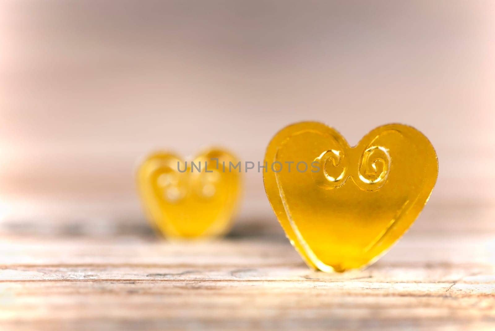 Two Golden Hearts on a Light, Wooden Background