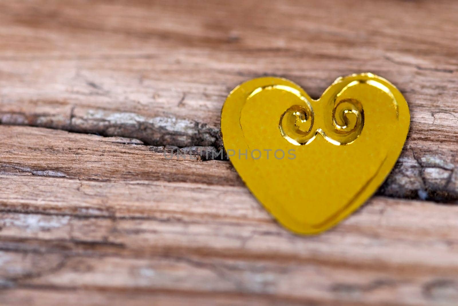 Golden little Heart lying on a cracked Wood Plank