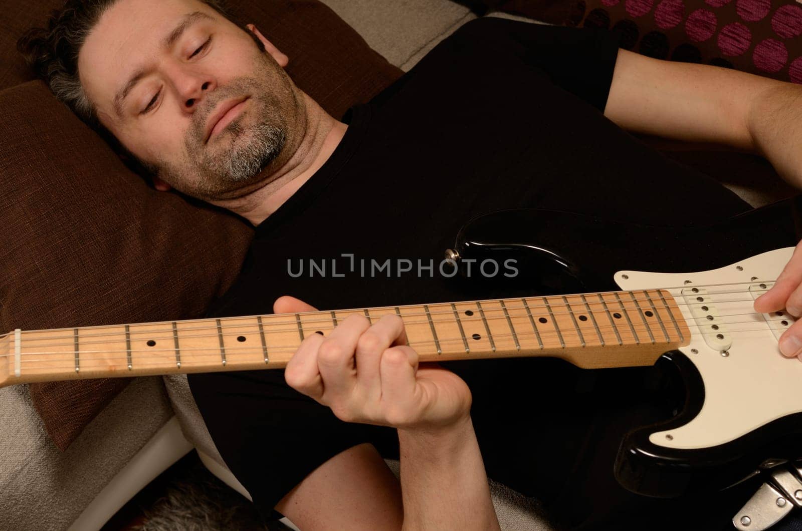 Man playing guitar on a couch