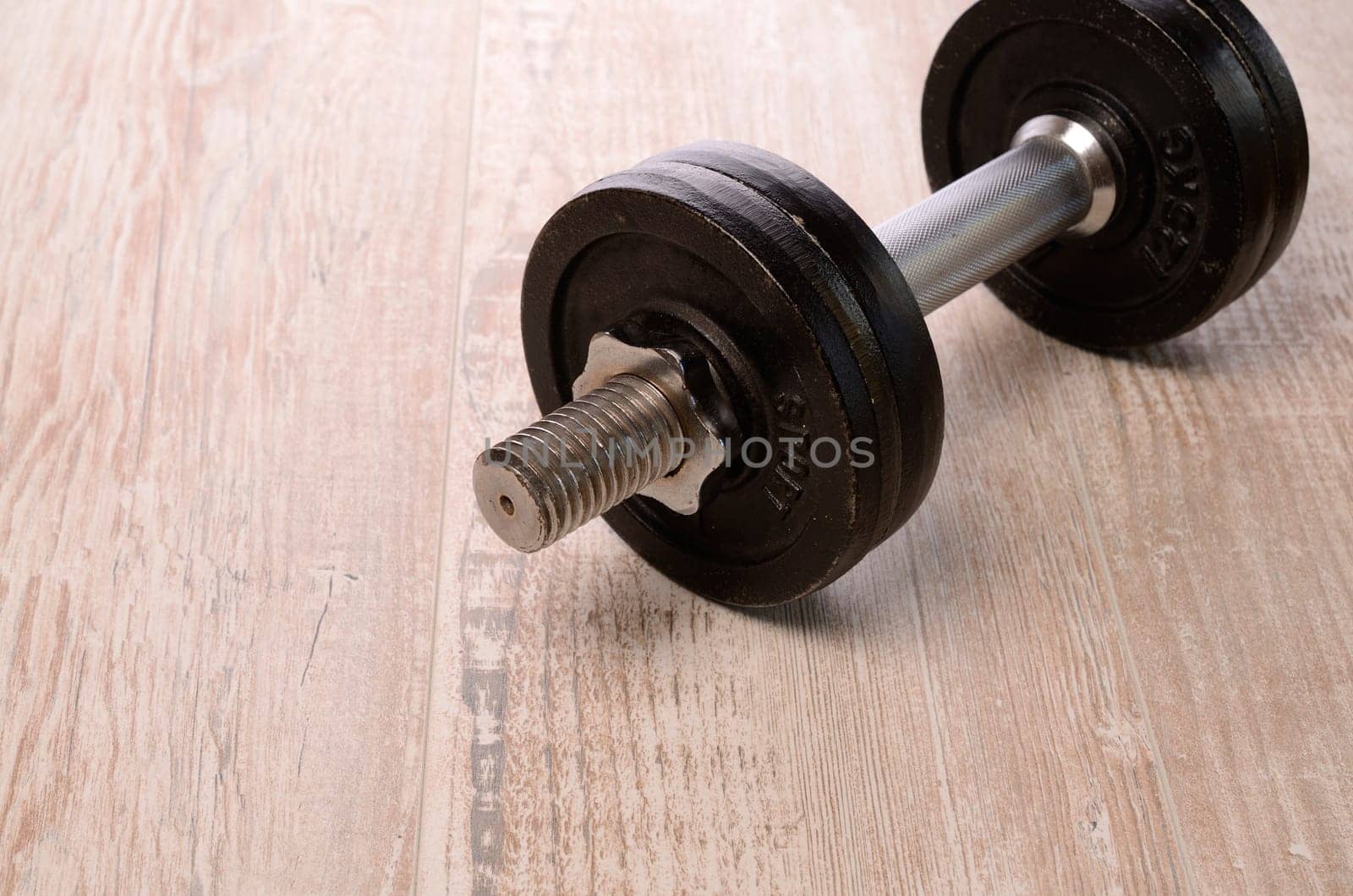 Fitness background with a dumbbell on a wooden floor with space for text