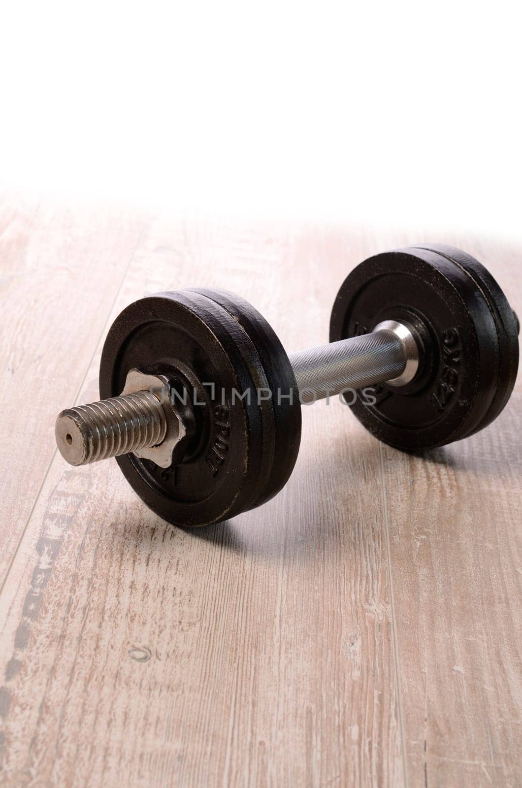 Fitness background with a dumbbell on a wooden floor with space for text