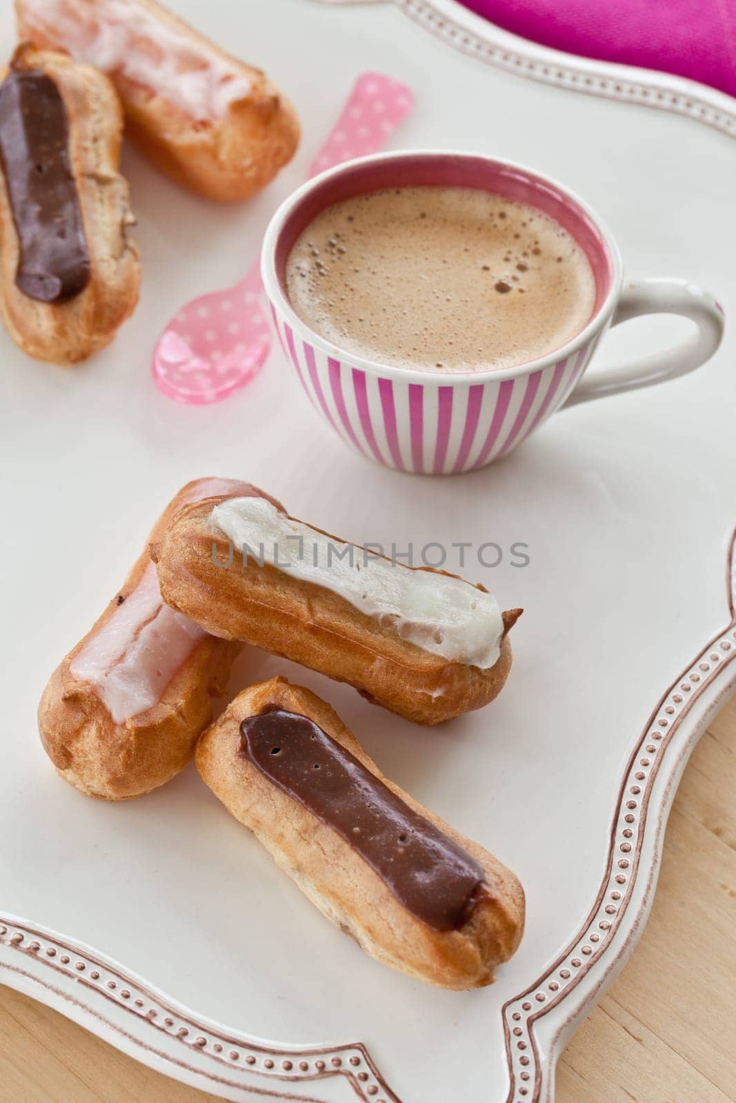 Selection of small eclairs with a cup of espresso
