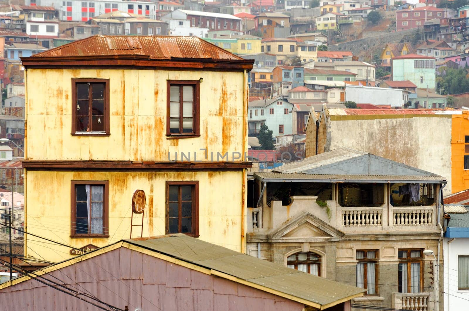 Yellow building with more buildings climbing up a hill in the background in Valparaiso, Chile
