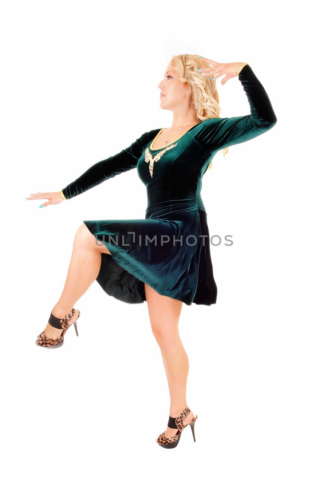A young pretty woman in a green dress dancing in the studio, isolated.over white background..