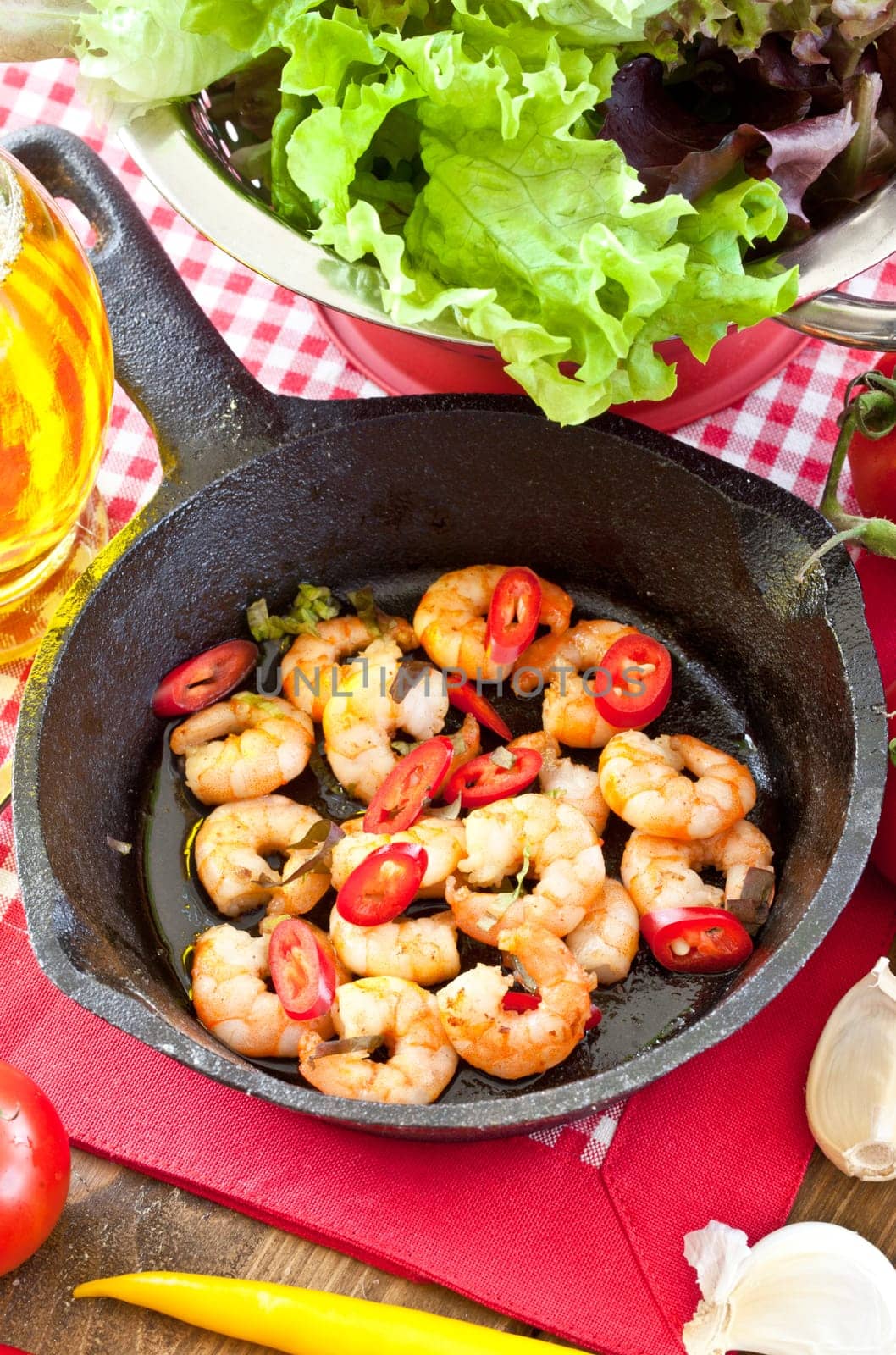 Fried shrimp with chilli in cast iron pan and fresh salad