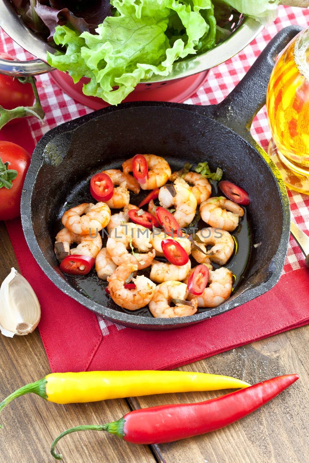 Fried shrimp with chilli in cast iron pan and fresh salad