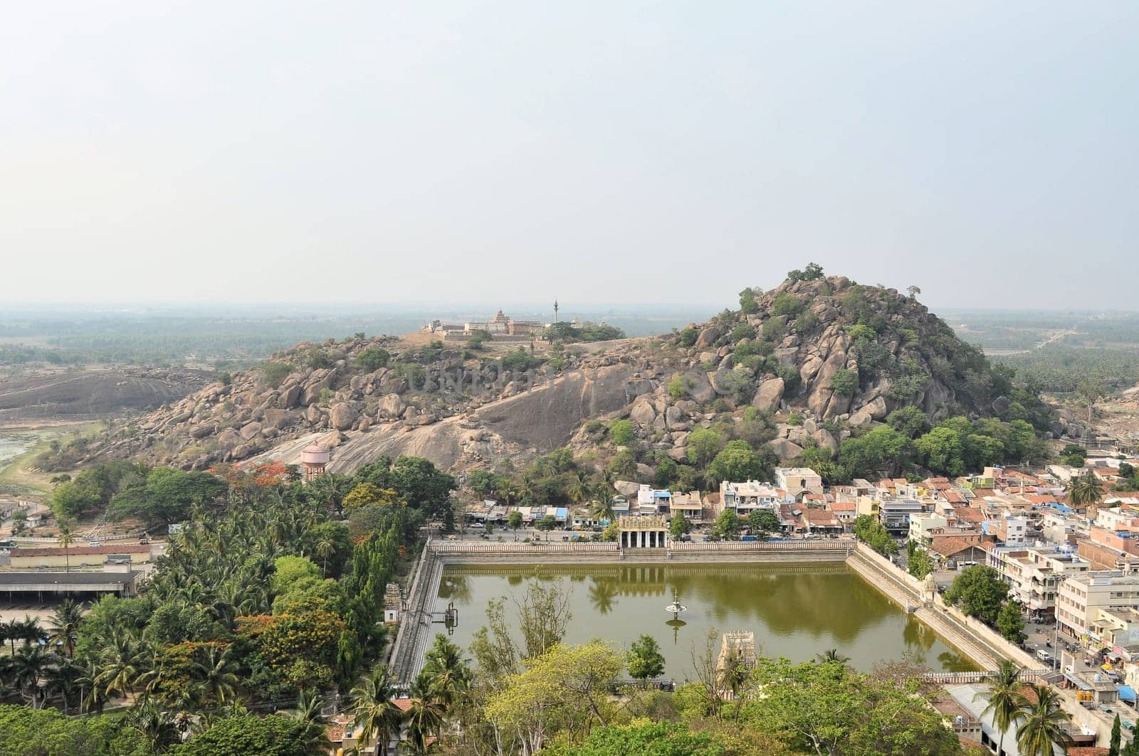 Traditional Hindu temple in lush landscape and green water tank in Shravanabelagola, India
