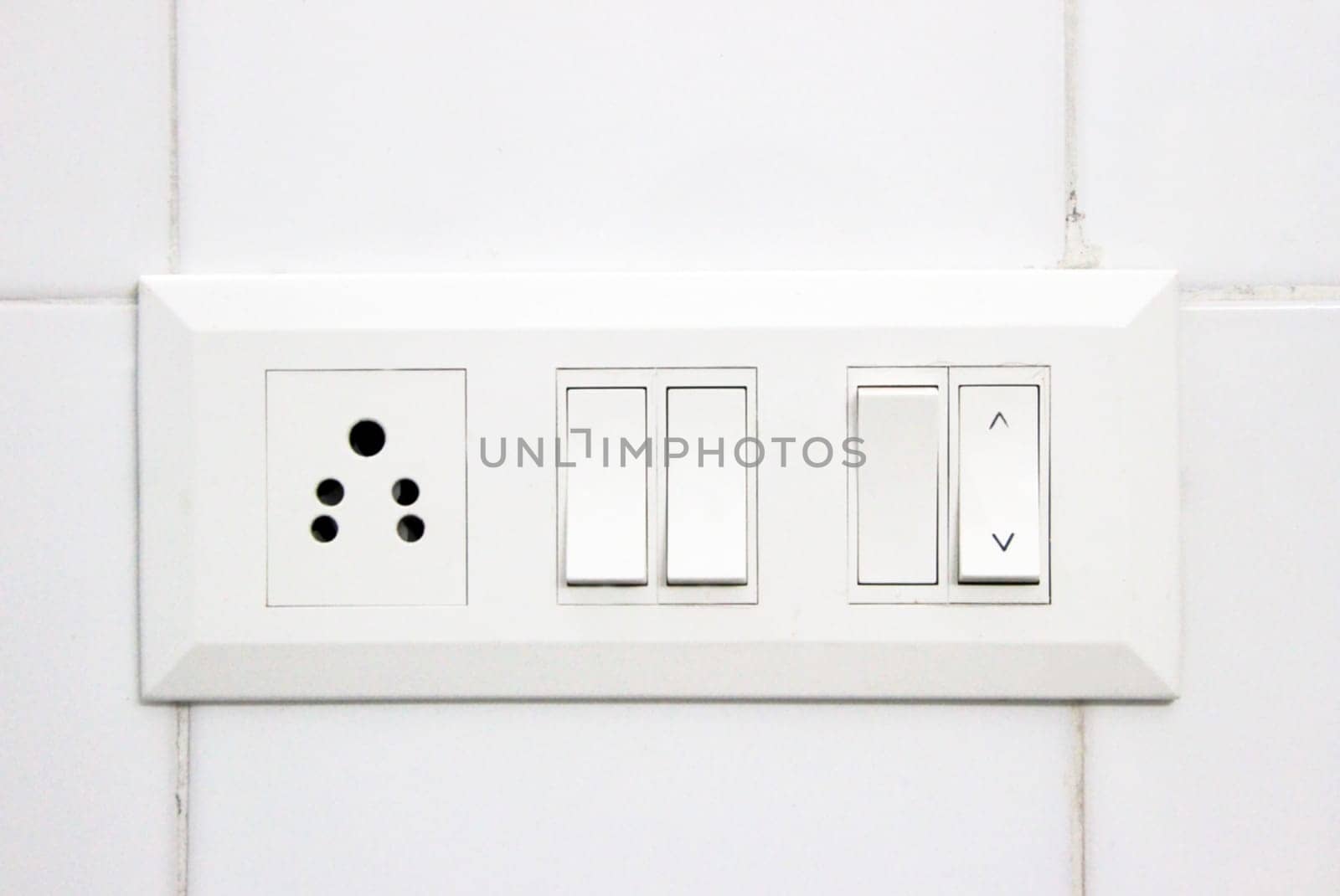 White electrical switch panel and plug point on white tiled wall