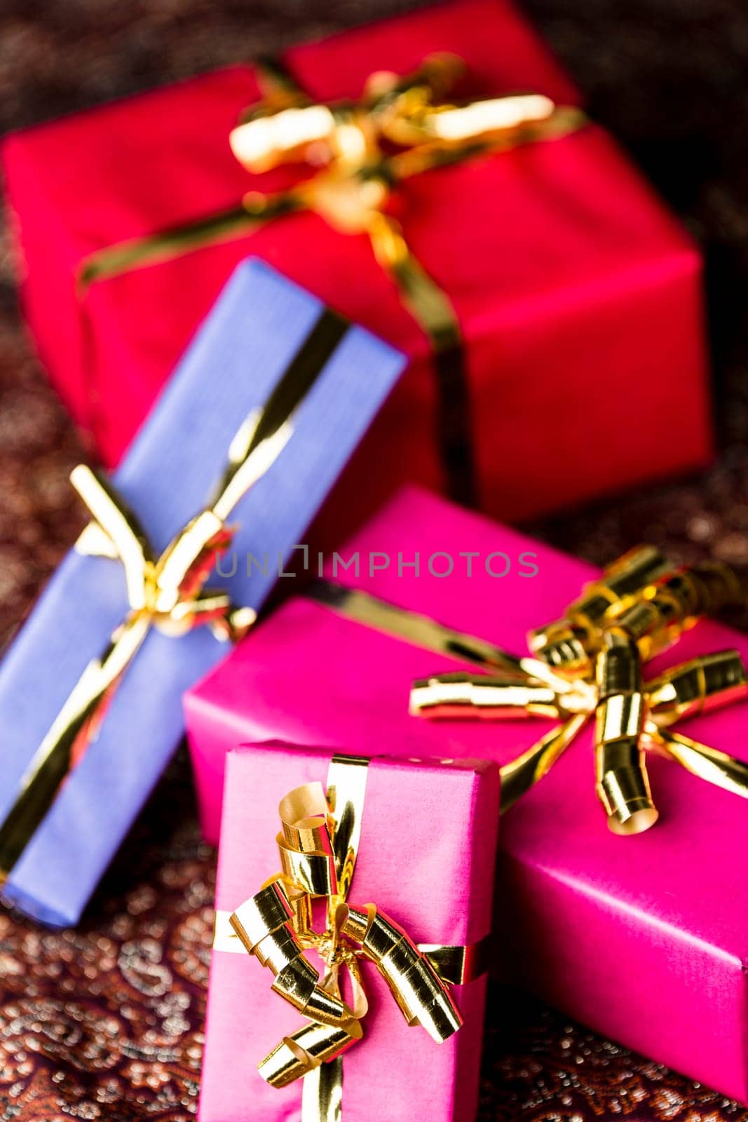 Presents packed for any occasion. Two packets in magenta, one in blue and one in crimson red. All tied with golden ribbons..