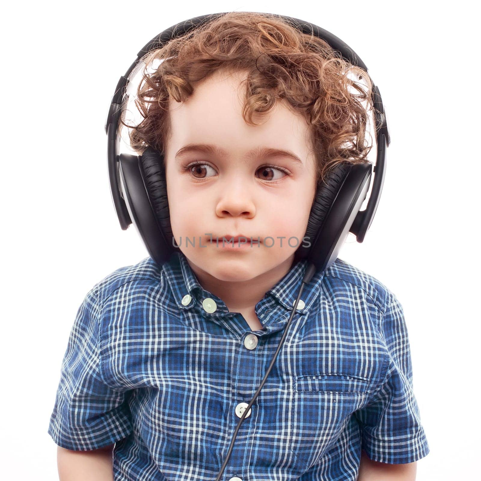 Toddler carefully listening to something in headphones