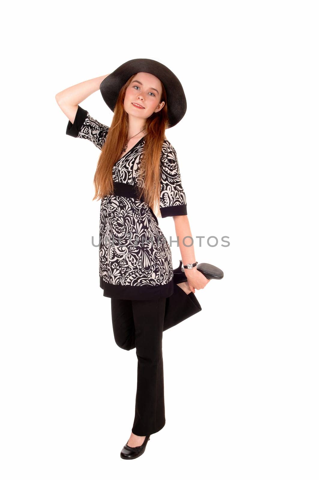 A young pretty woman in dress pants and a dress with a hat, standing.isolated over white background..