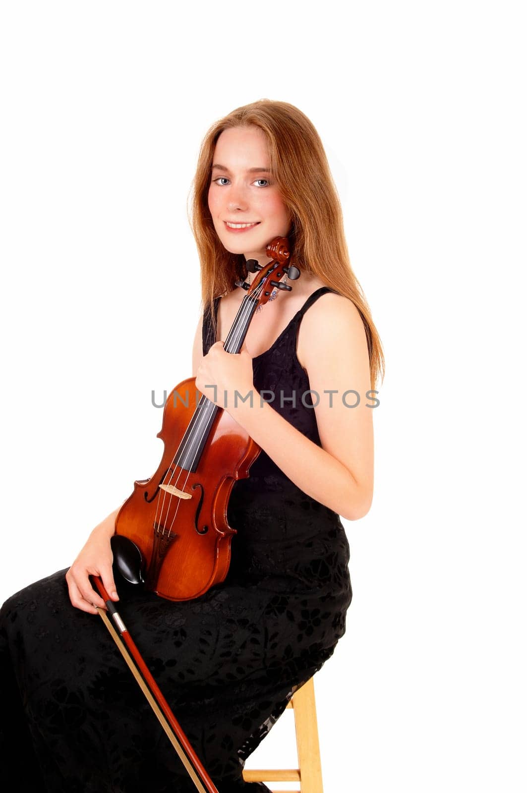 A pretty woman in a black dress sitting and holding her violin, smiling.into the camera, isolated for white background..
