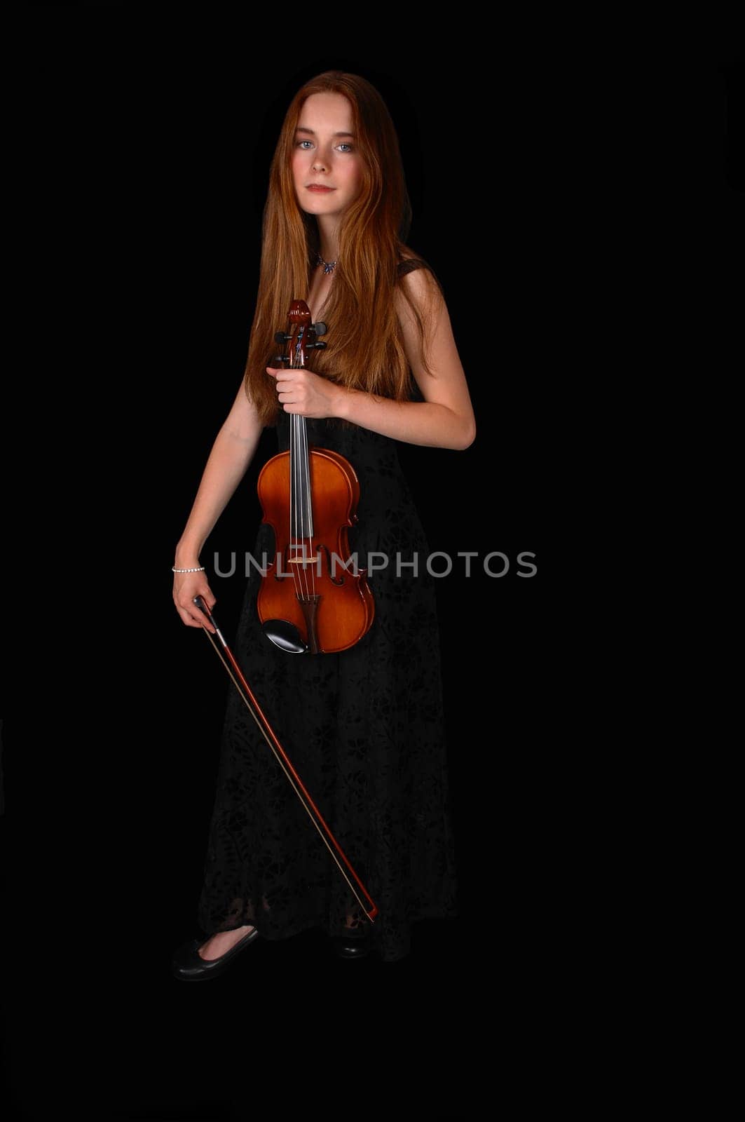A pretty woman standing for black background holding her violin..