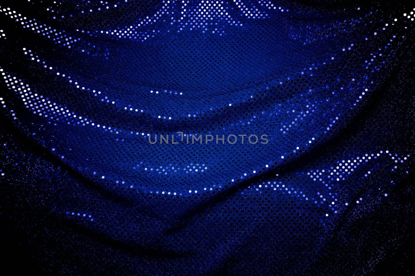 A dramatically draped piece of blue sequined fabric typically used to make dancer's costumes fills the image.